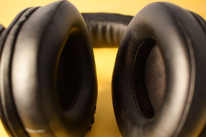 Close up of ears on headphone cushion on yellow background