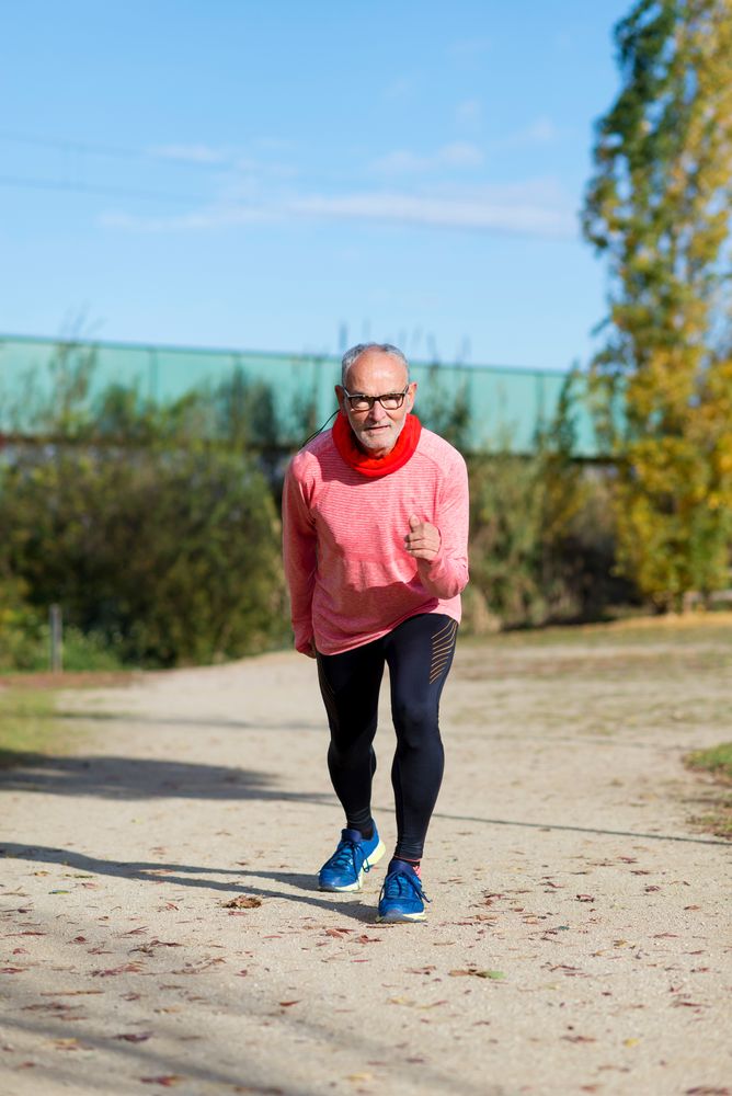 Grey haired man in red shirt and glasses in starting position for sprint