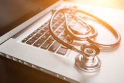 Medical Stethoscope Resting on Laptop Computer Keyboard.