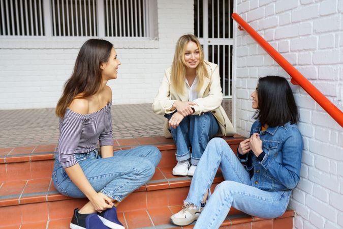 Three women sitting on brick stairs socializing