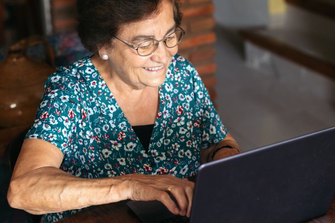 Older woman with glasses using a laptop at home