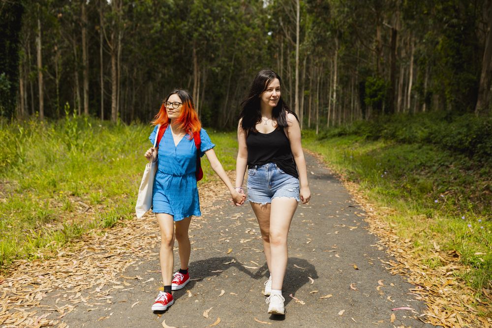 A couple of young lesbian women walk hand in hand along a rural path during a nature excursion in Galicia