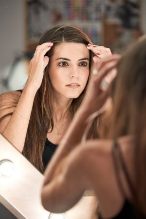 Charming woman looking at mirror in studio