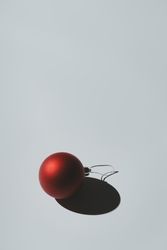 Red Christmas ornament with pastel grey background and deep shadows