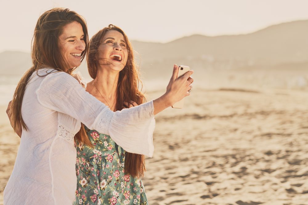 Smiling women making selfie on beach