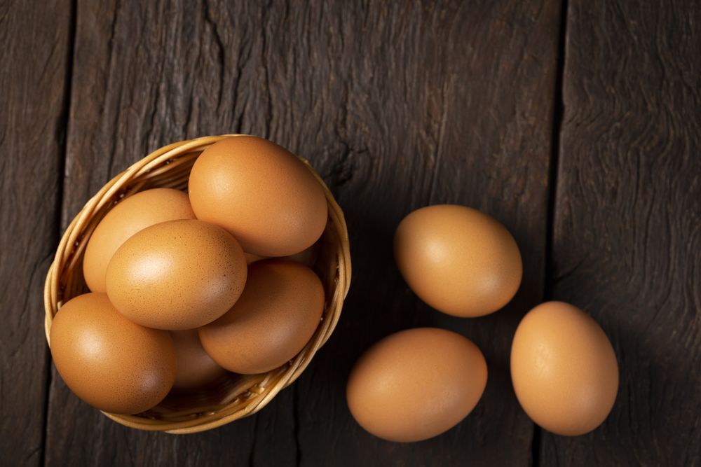 Basket with brown chicken eggs goes up the table.