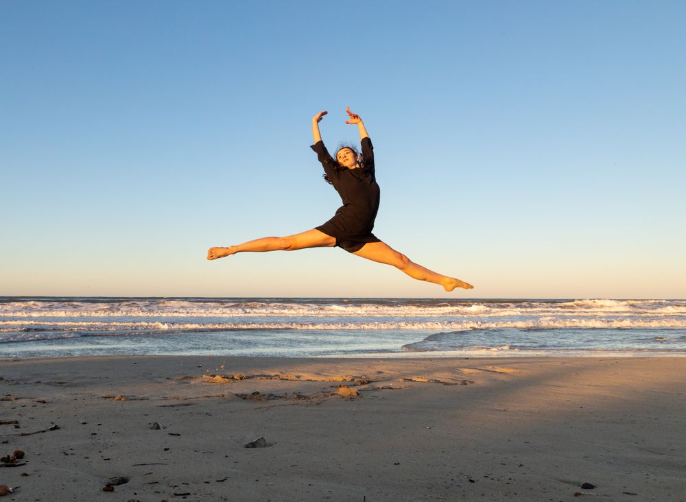 Woman jumping near water on shore