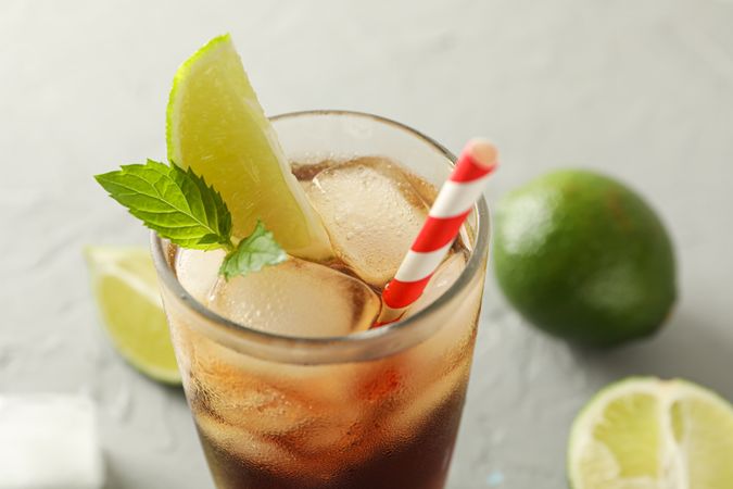 Glass with cold cola and citrus on grey cement background, space for text