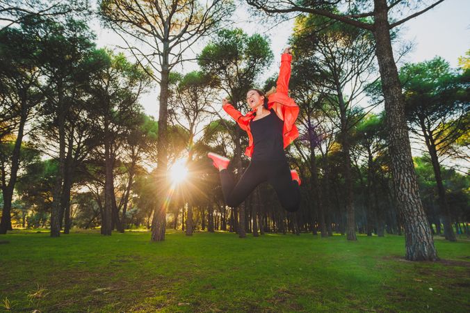 Jumping happy sportswoman on meadow