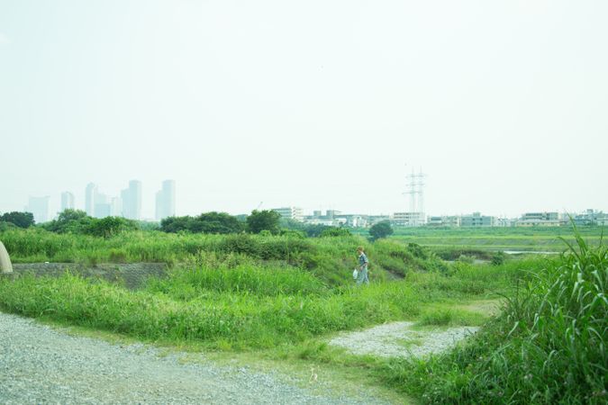 Man walking on green grass near factories
