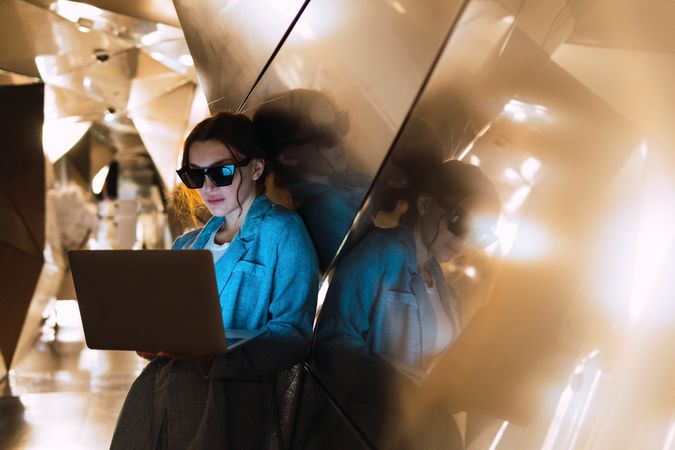 Woman in sunglasses browsing laptop in studio