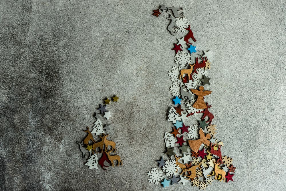Flat Christmas ornaments in two tree shapes on concrete background