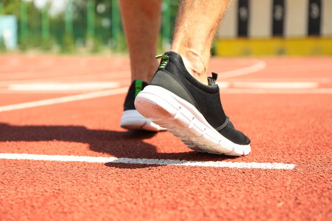 Man in sneakers on red athletic running track, close up