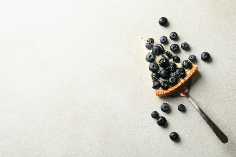 Spatula with blueberry pie slice on gray background