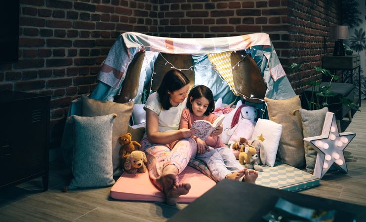 Mother and daughter having a pajama party reading a book