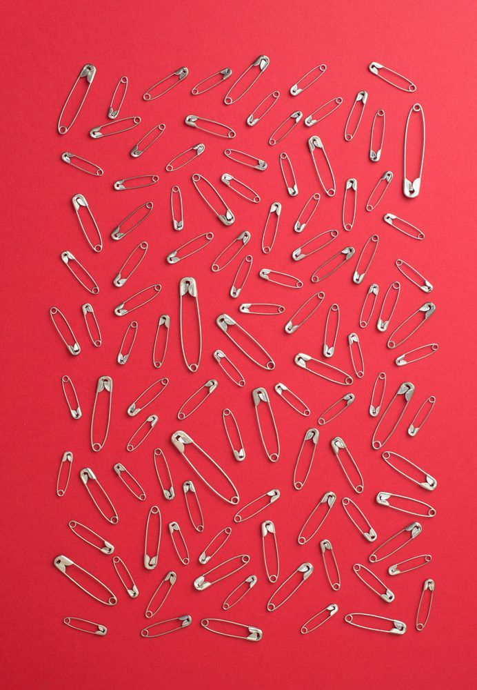 Scattered safety pins on red background