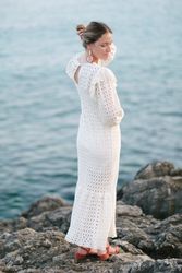 Romantic woman touching hair on rocky seashore
