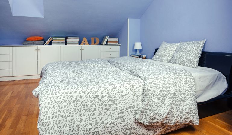 Bedroom in an attic with double bed with grey patterned duvet