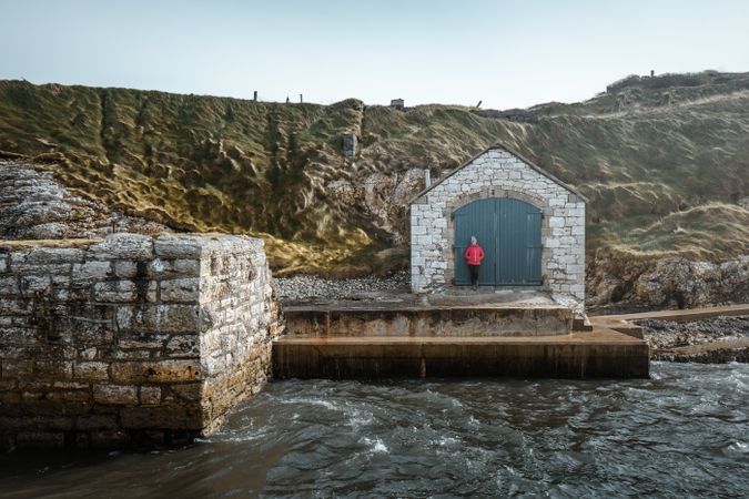 Woman relaxing beside aged building in quiet harbour