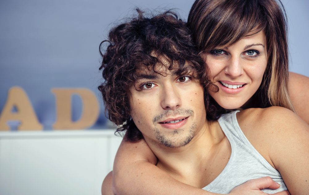 Portrait of couple in love embracing and smiling in bedroom