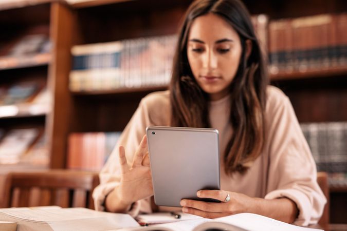 Female university student using digital tablet in library