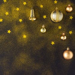 Golden Christmas decorations of stars, glitter bells and baubles on dark background