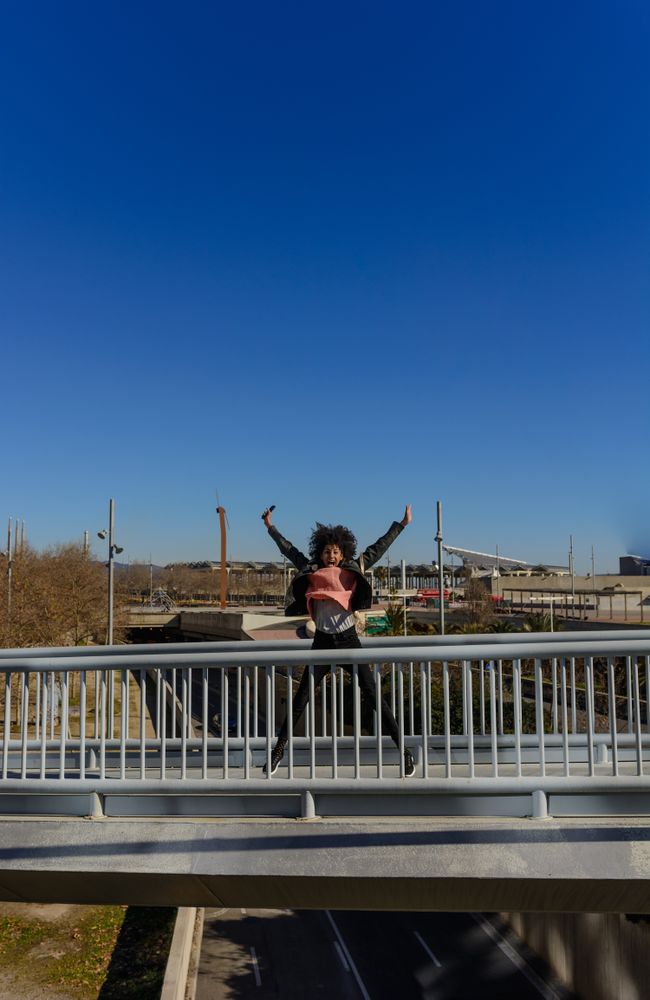 Woman with afro hair jumping for joy in the streets.