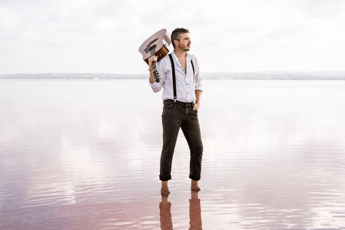 Inspired musician holding guitar at seaside
