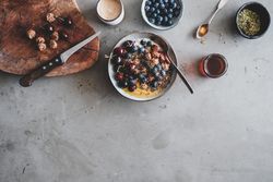 Oat granola yogurt bowl with cherries, blueberries, honey, nuts, coffee, wooden board
