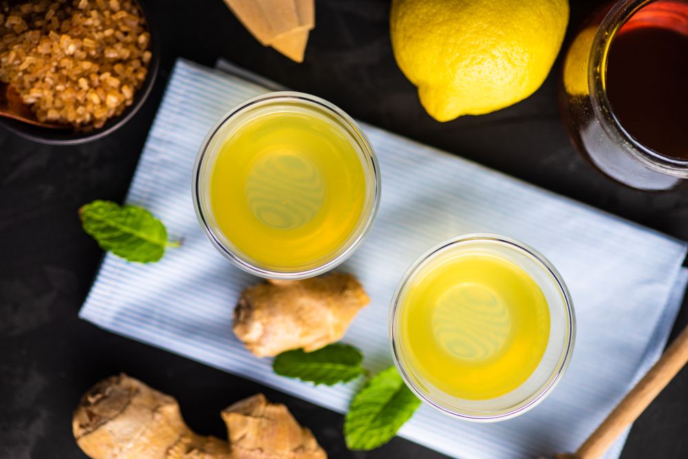 Top view of detox shots on napkin with lemon, ginger and mint on napkin