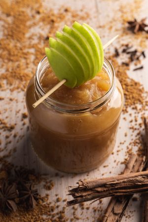 Delicious applesauce in glass jar and cinnamon
