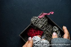 Hands holding box of thatched heart decorations  48BBdv