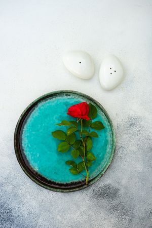 Top view of teal table setting with red rose