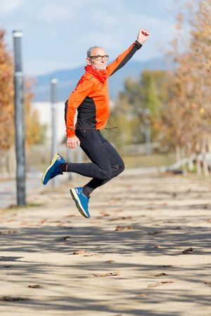 Side view of older man jumping in a park