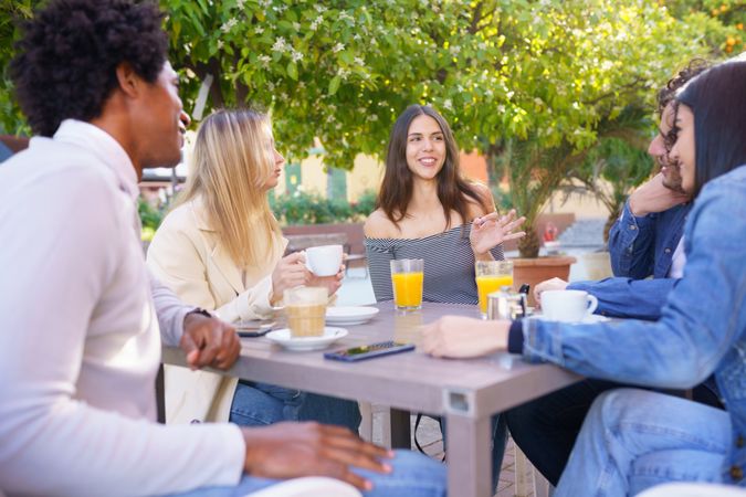 Multi-ethnic friends talking outside with drinks