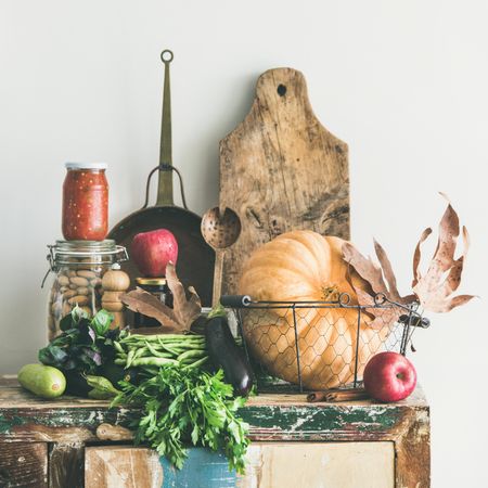 Fresh autumnal produce on kitchen counter, with squash, wooden board, apple, relish, square crop