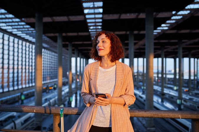 Smiling young woman holding phone at station