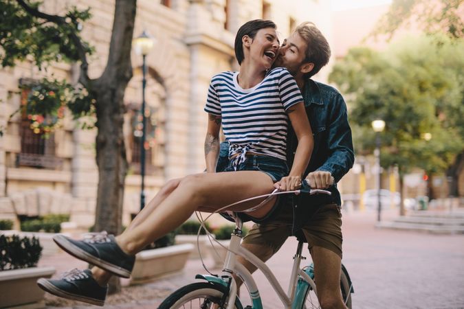 Laughing woman sitting on boyfriends bicycle handlebar