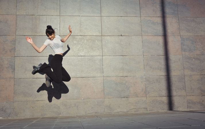 Woman jumping happily in the streets.