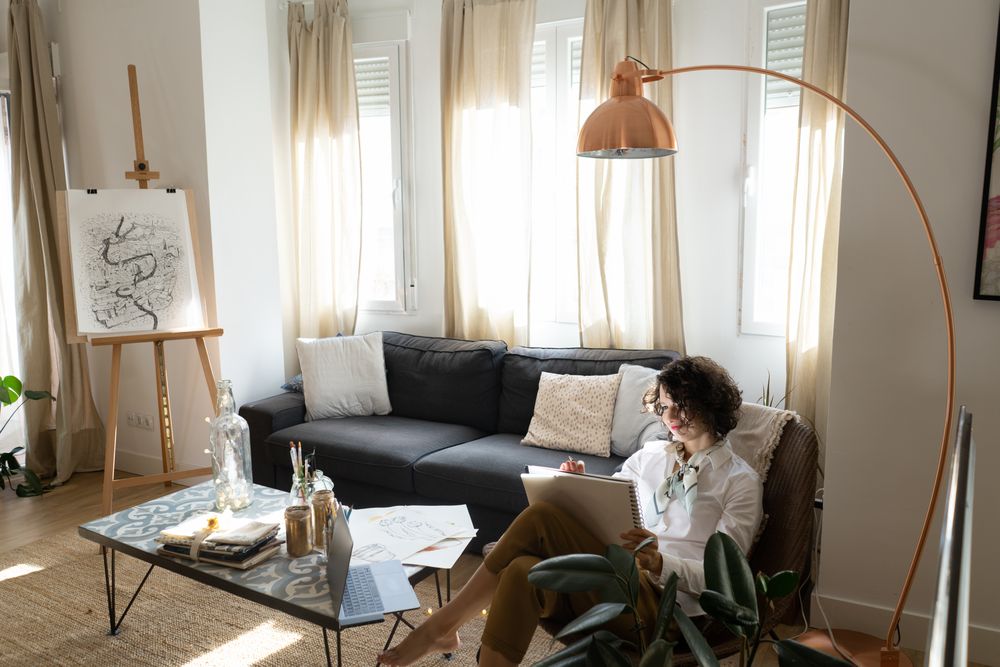 Woman writing on paper on sofa in room