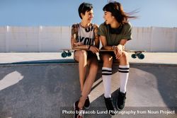 Women skaters sitting on a ramp with long board 4AODN0