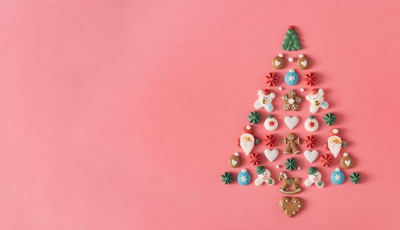 Festive tree made out of holiday cookies on salmon background
