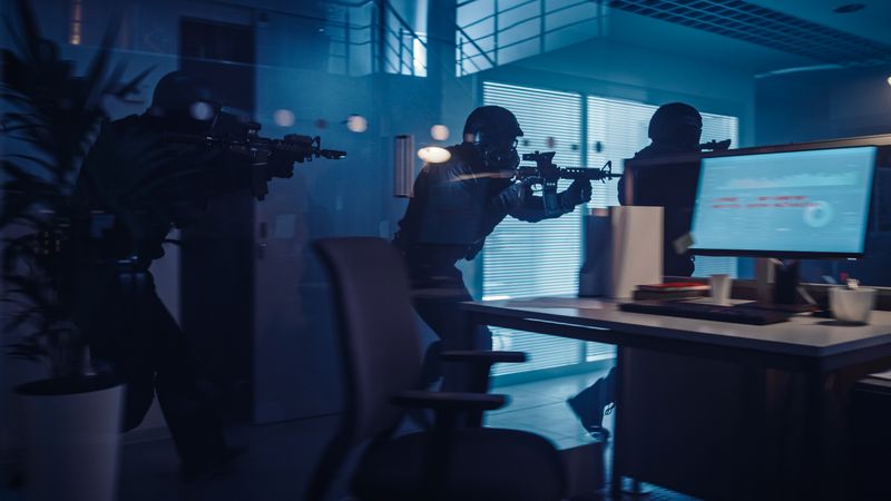 Masked Squad of Armed SWAT Police Officers Move in a Hall of a Dark Seized Office Building with Desks and Computers.
