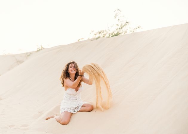 Woman having fun throwing sand in desert