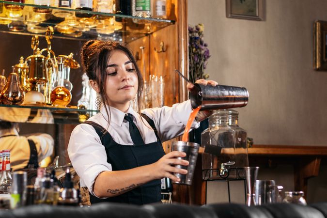 Female bartender preparing a cocktail in a traditional cocktail bar