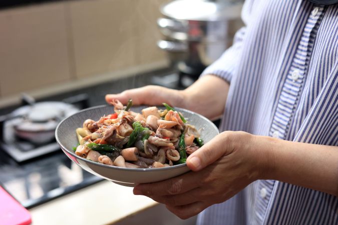 Female Hand Holding a Bowl with Cumi Cabe Ijo, Spicy Stir Fry Squid with Green Pepper
