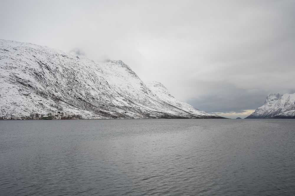 Tranquil lake against snowy hills in cold overcast weather