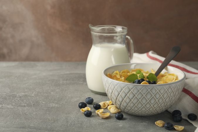 Concept of breakfast with muesli, milk and blueberry on gray table