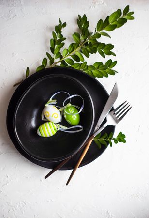Easter table setting with green decorative eggs and foliage on dark plate