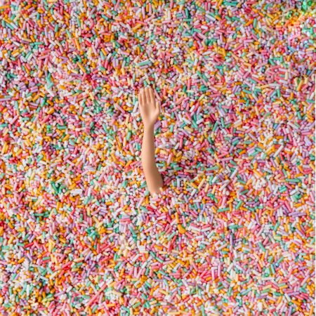 Doll arm buried in colorful sprinkles